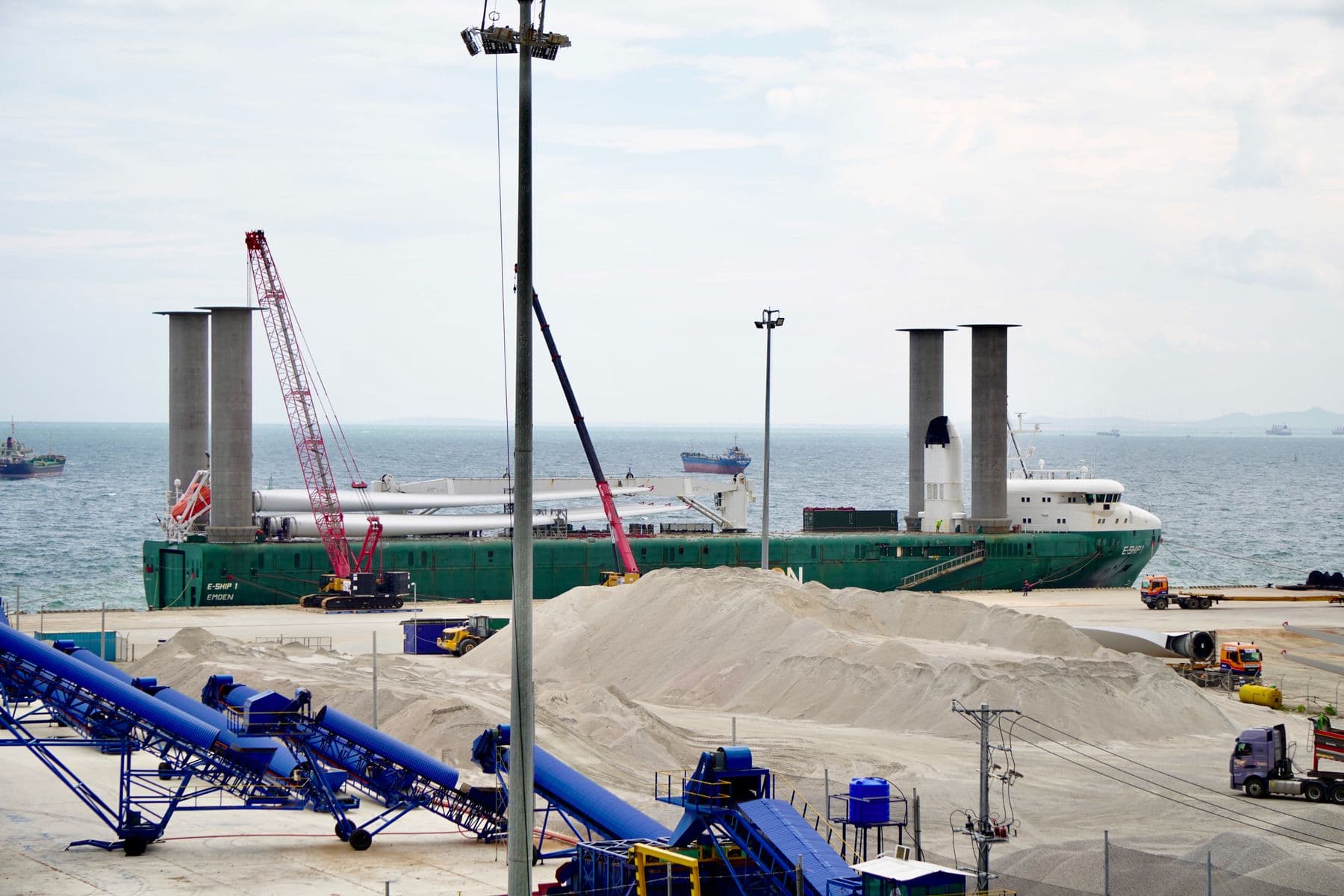 Dry bulk piles beside a ship at an industrial berth.